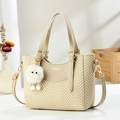 Beige woven tote bag with leather trim, crossbody strap and plush charm in lifestyle setting - 22cmx19cmx10cm / Khaki