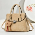 Elegant beige crossbody bag with silver bow accent and plush bear charm on white display - Khaki