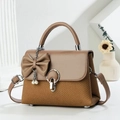 Detail of a brown textured crossbody bag with a large bow, pearl chain, and round metal lock - Dark Khaki