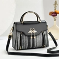 Chic tweed crossbody bag with black leather flap and golden swan pendant on white desk - Black