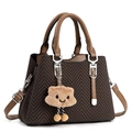 Close-up of dark brown woven texture handbag with light brown leather trim and plush charm - Coffee