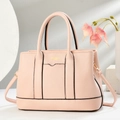 Borsa tote in pelle martellata rosa con scritte dorate esposta su una base di pietra - Rosa