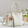 Elegant cream woven tote bag with brown bear charm and adjustable strap on a clean background - Off-white