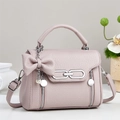 Detail of dusty rose litchi grain leather bag with bow, pearl charm, and silver hardware - Pink