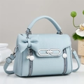 Details der hellblauen Lederhandtasche mit Schleife, Silberring und Perlenanhänger - Blau