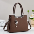 Detalle de bolso trapezoidal marrón oscuro con colgante de estrella plateada y perlas - café