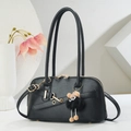 Retro black leather tote bag with gold hardware and plush monster charm on modern background - Black