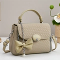 Detail of beige crossbody bag featuring textured weave, M buckle, and pearl bow charm - Yellow-Green