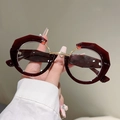 Dettaglio di montatura bordeaux irregolare con ponte in metallo dorato e tagli geometrici - Rosso Vino Montatura Oro Lente Trasparente