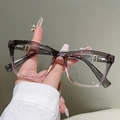 Makroaufnahme der grau-rosa quadratischen Brille mit goldenen Metallakzenten für Damen - Grau Rosa Verlauf Rahmen Klare Linse