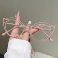 Detail of pink cat-eye glasses with unique hollow metal frame held by a model - Pink Frame Clear Lens