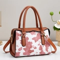 Detail of pink cow print tote bag with brown leather handles and gold-tone metal hardware - Pink