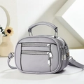 Detalle de bolso bandolera gris claro con textura de grano y cremalleras plateadas - Púrpura Claro