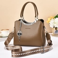 Brown faux leather handbag with geometric strap and heart lock pendant on a desk - Dark Khaki