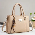 Detail of beige lychee grain leather bag featuring silver lock and decorative woven pendant - Khaki