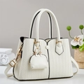White woven tote bag with gold hardware and mini pouch charm on a minimalist desk - Off White