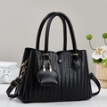 Classic black woven tote bag with dual handles and gold hardware in an elegant setting - Black