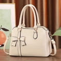 Close-up of litchi texture beige bag with bow detail and gold-tone hardware - Off White