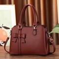 Close-up of deep red lychee texture leather handbag with bow and metal rivet detail - Dark Red