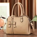 Detail of light brown lychee textured tote bag with bow accent and golden studs decoration - Khaki