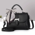 Close-up of black leather handbag with silver buckle and decorative silk scarf handle - Black