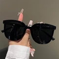 Dettaglio degli occhiali da sole neri oversize lucidi tenuti in mano per stile - Montatura Nera Originale
