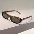Detail of vintage oval tortoiseshell sunglasses on a minimalist grey geometric stand - Leopard Frame Green Lens