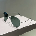 Primer plano de gafas de sol aviador polarizadas sin montura en un soporte minimalista - Verde Oscuro