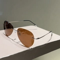 Detalle de gafas de sol polarizadas sin montura con lentes marrones y patillas de plata - Lentes Color Té Oscuro