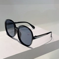 Macro shot of stylish oversized round black sunglasses with dark blue tinted lenses - Black Frame Grey Lens