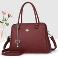 Detalle de bolso burdeos de cuero granulado con colgante de gato plateado y logo de marca - Granate