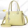 Detail of lime green tote bag featuring silver heart pendant and metal brand logo - Green