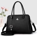 Detalle de bolso en cuero granulado negro con logo plateado y colgante gato sobre fondo gris - Negro