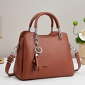 Brown litchi grain trapezoid handbag with twin handles and star charm on grey background - Earthy Yellow