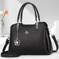 Dettaglio della pelle martellata nera con logo argento e ciondolo a fiore sulla borsa - Nero