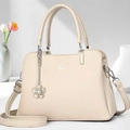 Dettaglio della borsa in pelle beige con finiture argento e ciondolo a fiore - Albicocca