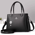 Close-up of black lychee leather handbag with metal logo and cute panda pendant - Black