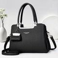 Detail of black lychee grain leather handbag with silver metallic handle and mini pendant - Black