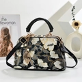 Detail of floral embroidery on a vintage handbag with a gold leaf pendant and pearl decor - Black