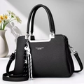 Detail of black pebbled leather handbag with silver hardware and chic woven charm - Black