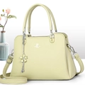 Close-up of lychee grain leather tote with silver logo and floral charm detail - Green