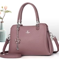 Close-up of pink pebbled leather handbag with silver logo and floral charm detail - Purple