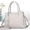 Detail of light gray lychee grain leather handbag with silver flower charm and long strap - Gray