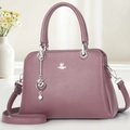 Detailed view of mauve lychee leather handbag with silver logo and heart charm accessory - Purple