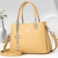 Yellow leather handbag with David Jones logo and floral pendant on a white background - Yellow