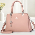 Detailed view of pink faux leather handbag with silver logo and heart chain charm - Pink