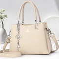Détail du sac à main en cuir beige avec breloque trèfle en perles et finitions argent - Abricot