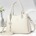 Macro shot of silver hardware and pearl flower charm on cream leather handbag - Off-white