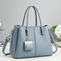 Close-up of light blue lychee pattern leather tote bag with silver hardware and mini charm - Blue