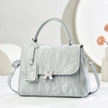 Detail of grey wrinkled glossy bag with butterfly buckle and metal floral pendant - Gray